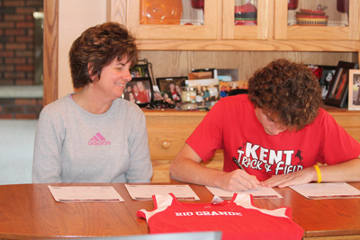 Roosevelt High’s Nate Goodhart signs a letter of intent to run at the University of Rio Grande as his mother, Elaine, watches